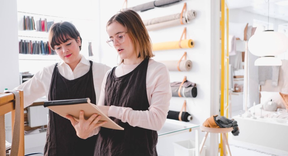 Two women looking over clothing design on notepad