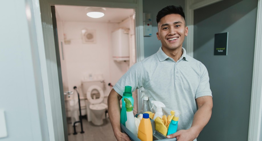 smiling man holding tray of cleaning supplies