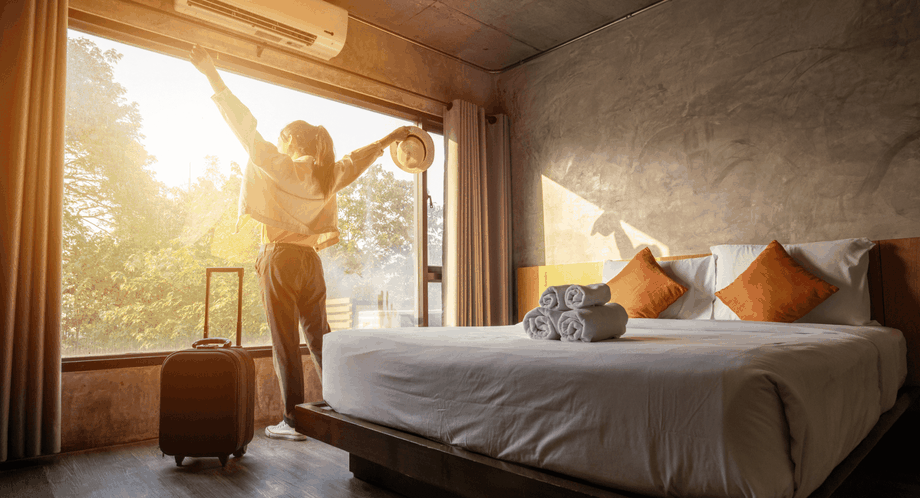 Woman with outstretched arms admiring sunrise view of hotel room