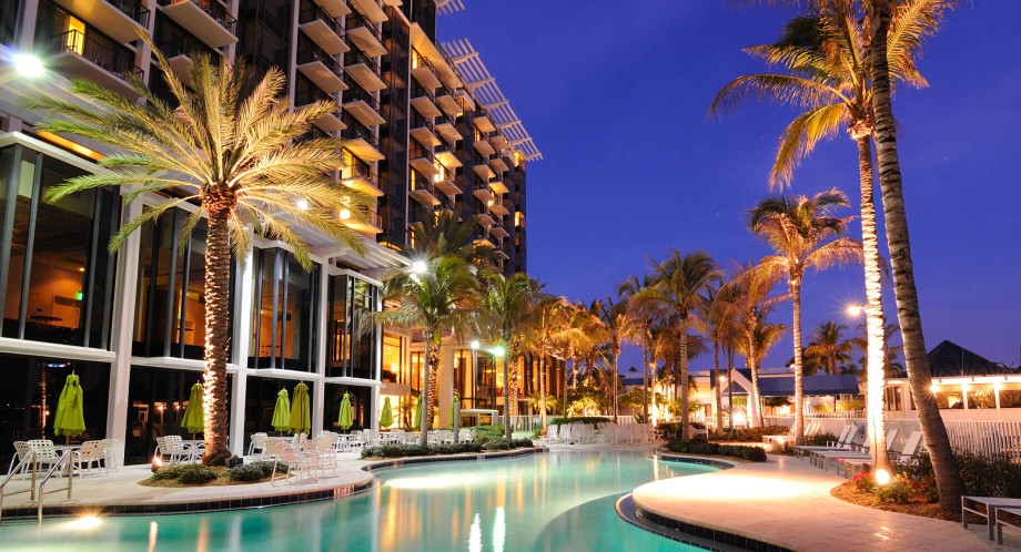 A hotel pool at night with palm trees and lights